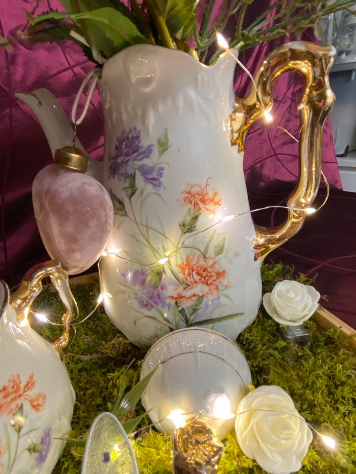 Alte Kaffekanne dekoriert mit Blumen und Licht in Dinslaken