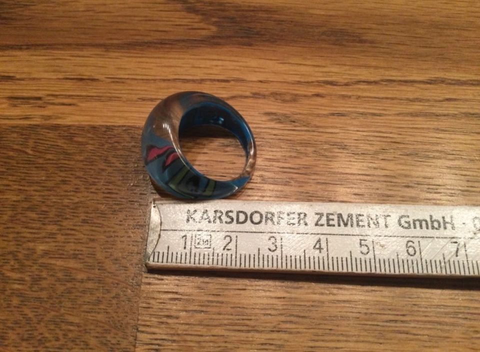 Blau farbener Ring aus Kunststoff mit rot-grünen Verzierungen in Nickenich