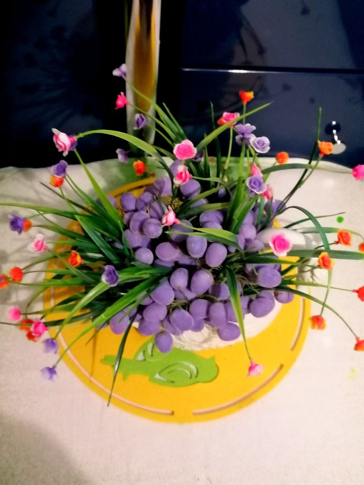 Osterdeko: Pflanzgefäße Schwan mit kleinen lila Eiern und Blumen in Raunheim