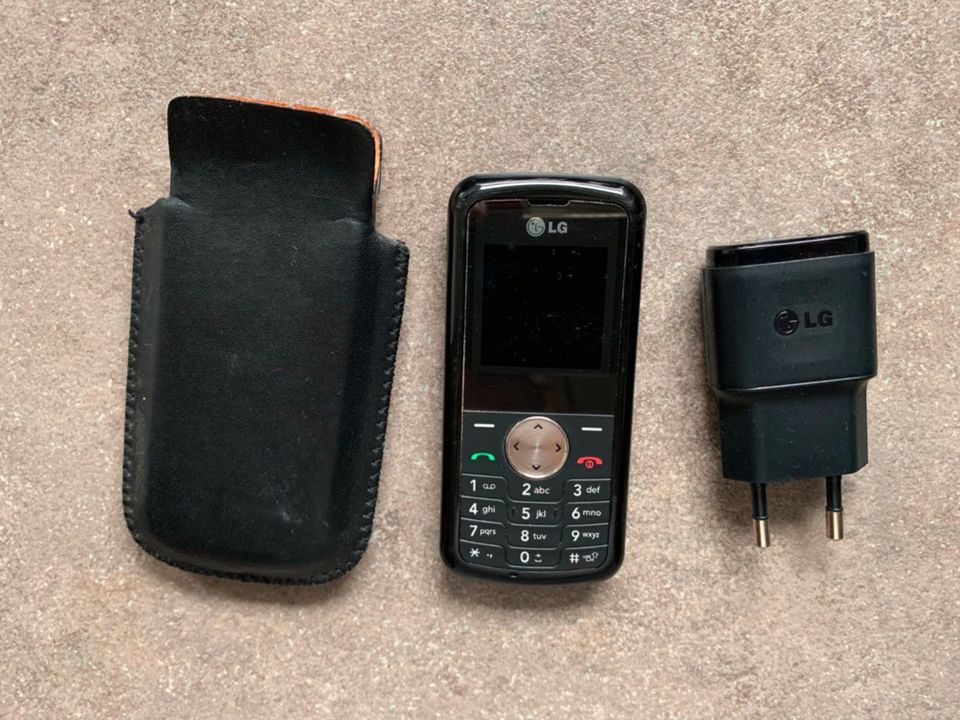 LG Handy mit Lederhülle und Ladegerät in Schwabstedt