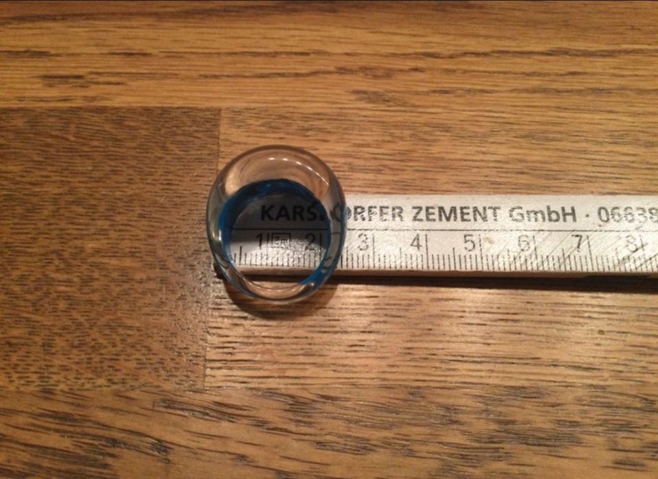 Blau farbener Ring aus Kunststoff mit rot-grünen Verzierungen in Nickenich