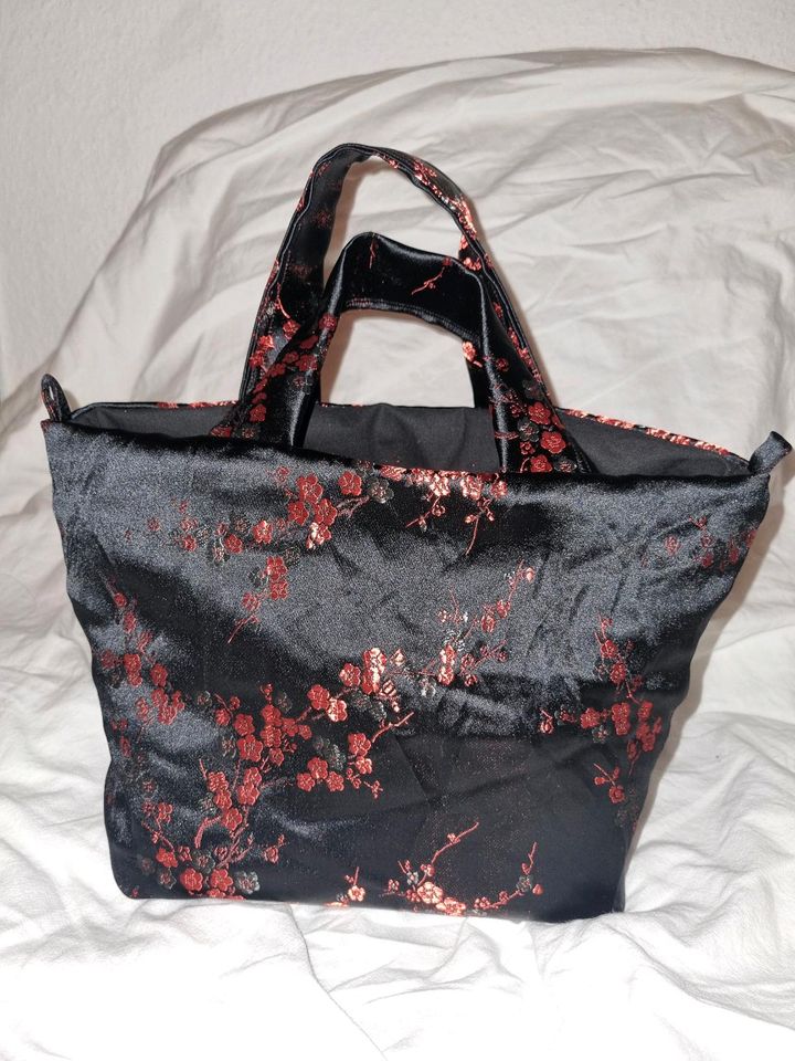 Schwarze Handtasche mit roten Blumen in Köln