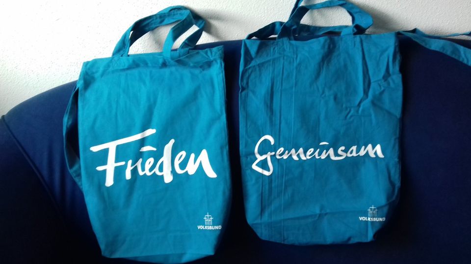 2 blaue Stofftaschen mit den Aufdrucken Frieden und Gemeinsam in Augsburg