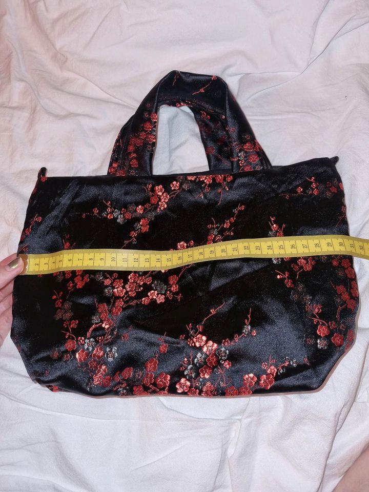 Schwarze Handtasche mit roten Blumen in Köln